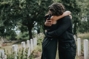 A man and woman embracing in a graveyard after a wrongful death.